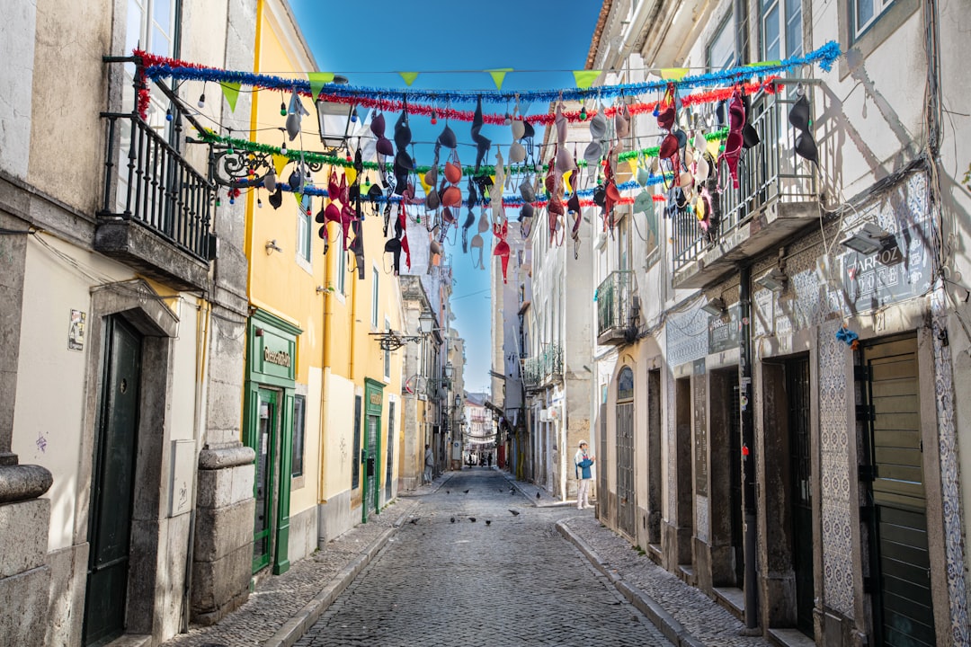 Colorful buildings lining a Lisbon street with spring flowers on balconies