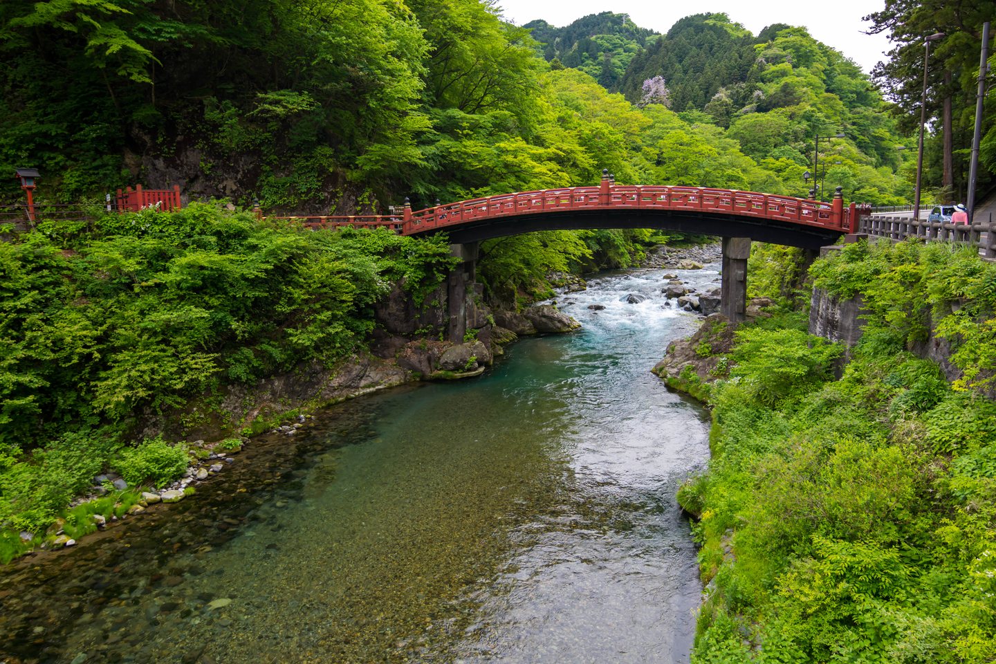 สะพานชินเคียวสีแดงทอดข้ามแม่น้ำไดยะ ท่ามกลางต้นไม้สีเขียวในนิกโก้